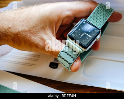 PARIS, FRANCE - APR 24, 2018: New Apple Watch Series 3 smartwatch personal wearable device in male hand with the new 42mm Marine Green Sport Loop  - unboxing of strap Stock Photo
