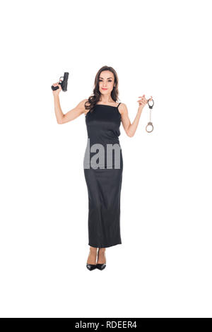 beautiful female secret agent in black dress holding gun and handcuffs, isolated on white Stock Photo