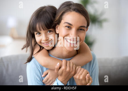 Happy mom and cute kid daughter embracing looking at camera Stock Photo