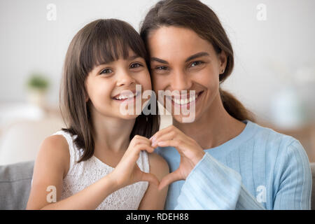 Cute daughter and happy mother join hands in heart shape Stock Photo