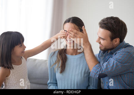 Cute kid and loving husband making unexpected surprise for mom Stock Photo