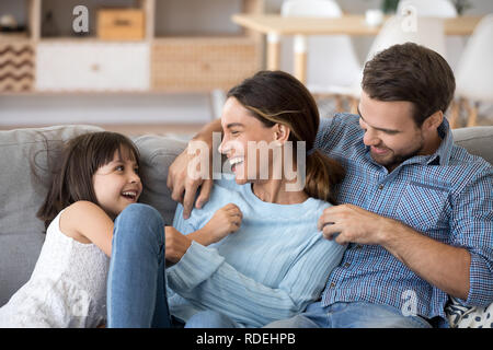 Kid daughter and dad tickling mom having fun playing together Stock Photo