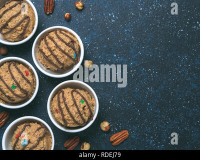 Safe-to-eat raw monster cookie dough in small portion bowl on dark blue background. Ideas and recipes for kids and toddlers meal. Top view or flat-lay. Copy space for text. Stock Photo