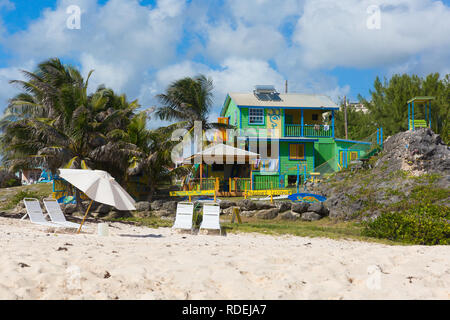 A multi-coloured beach house appartment on Silver Sands beach on Barbados, palm trees, sun loungers, white sand