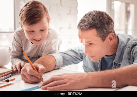 Blonde-haired son watching his father drawing figures for geometry class Stock Photo