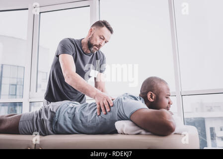 Attentive bearded man doing massage to his patient Stock Photo