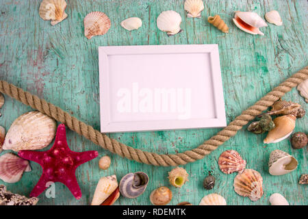 white wooden blank frame,rope and the collection of sea shells on a vintage shabby background Stock Photo