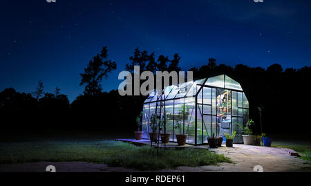 Stars behind a small greenhouse that is lighted for the night Stock Photo