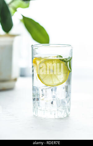 glass cup and a carafe of water, ice, mint and lemon on a white table Copy space Stock Photo