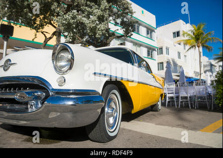 MIAMI - DECEMBER 31, 2018: Bright scenic view of classic American car complementing the Art Deco architecture of Ocean Drive on South Beach.