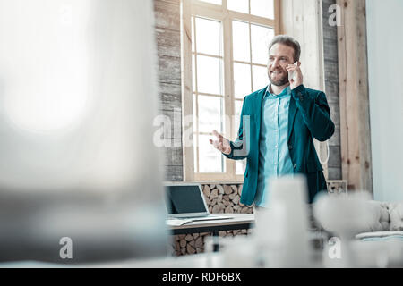 Bearded businessman wearing dark blue jacket speaking on phone Stock Photo