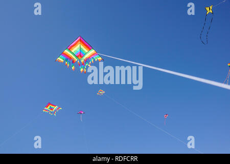 angle view of a colorful kite flying with waving red bow in a deep blue sky with the light of the sun Stock Photo