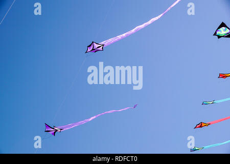 angle view of a colorful kite flying with waving red bow in a deep blue sky with the light of the sun Stock Photo