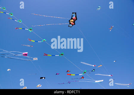 angle view of a colorful kite flying with waving red bow in a deep blue sky with the light of the sun Stock Photo