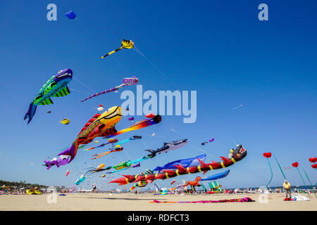 angle view of a colorful kite flying with waving red bow in a deep blue sky with the light of the sun Stock Photo