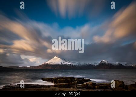 Big rocks in the water of the North Sea with snow-covered Cullin mountains in the background, Elgol, Isle of Skye, Scotland Stock Photo