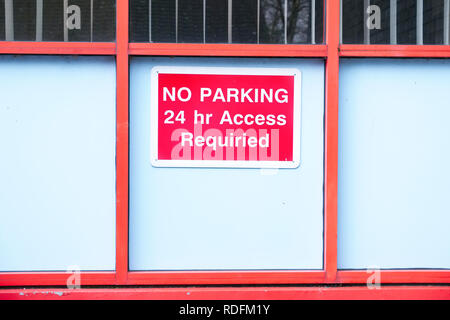 No parking 24 hour access sign red and white on wooden school wall Stock Photo