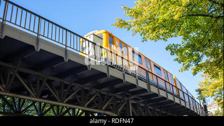 Transportation means. Yellow electric train on steel bridge, Berlin, Kreuzberg east side, Germany. Under view. Stock Photo