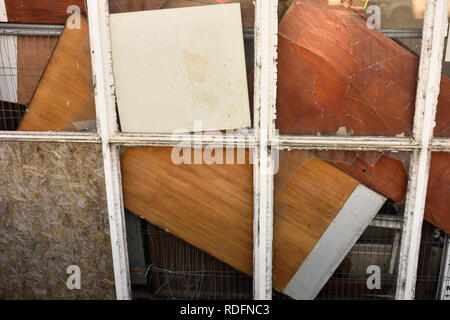 Broken windows boarded up with loose wooden panels in bury lancashire uk Stock Photo