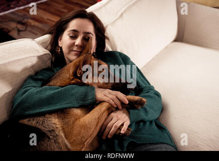 Beautiful portrait of smiling woman hugging her dog german shepherd together in front of fireplace at cozy home in winter day in happiness Friendship  Stock Photo