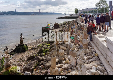 Man stacking stones on the bank of the Tagus River in Lisbon, Portugal Stock Photo