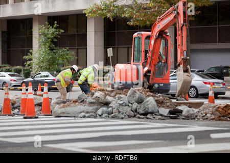 Municipal workers digging asphalt to perform underground repairs - USA Stock Photo