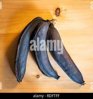 A bunch of rotten bananas that have turned black on a wooden board Stock Photo