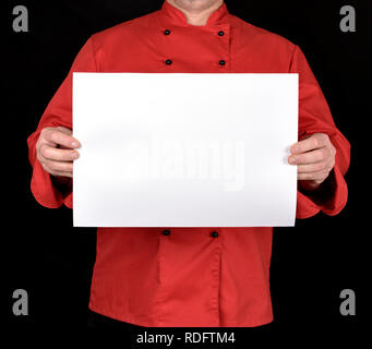 chef in red uniform holding a blank white paper sheet on a black background, copy space Stock Photo