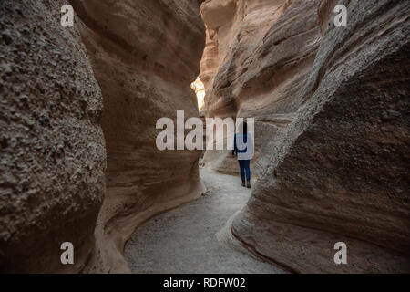 Woman hiking in the Beautiful American Canyon Landscape during a sunny evening. Taken in Kasha-Katuwe Tent Rocks National Monument, New Mexico, United Stock Photo