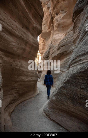 Woman hiking in the Beautiful American Canyon Landscape during a sunny evening. Taken in Kasha-Katuwe Tent Rocks National Monument, New Mexico, United Stock Photo