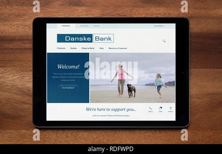 The website of Danske Bank is seen on an iPad tablet, which is resting on a wooden table (Editorial use only). Stock Photo