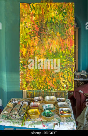 A table with mixed colours in trays used on painting which is in progress on the easel. Stock Photo