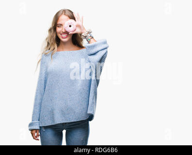Beautiful young blonde woman eating pink donut over isolated background with a happy face standing and smiling with a confident smile showing teeth Stock Photo