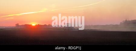 Tractor in Field at Sunset Stock Photo