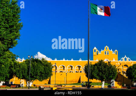 Beautiful monastery of Izamal painted all yellow with a colonial architecture and the Mexican flag floating in Yucatan, Mexico Stock Photo