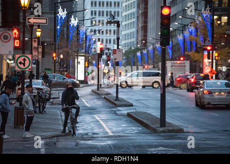 MONTREAL, CANADA - NOVEMBER 7, 2018: Cyclist, delivery courrier guy, standing with his bicycle on a bicycle lane in downtown center business district  Stock Photo