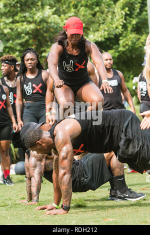 An athletic woman jumps over her male teammates as they compete in the over unders event at Atlanta Field Day on July 14, 2018 in Atlanta, GA. Stock Photo