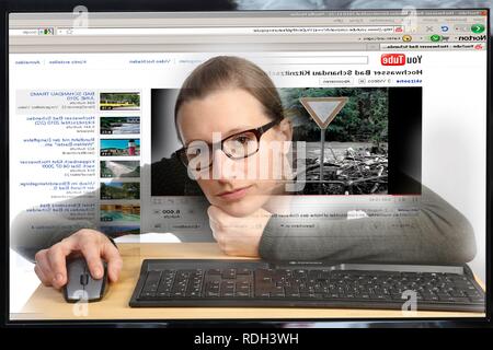 Young woman sitting at a computer surfing the Internet, viewing a video on the YouTube site, view from within the computer Stock Photo