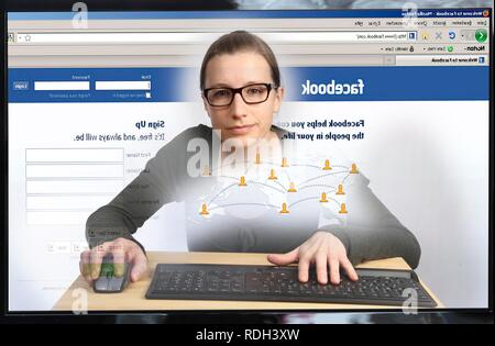 Young woman sitting at a computer surfing the Internet, viewing a page of Facebook, a social networking site Stock Photo