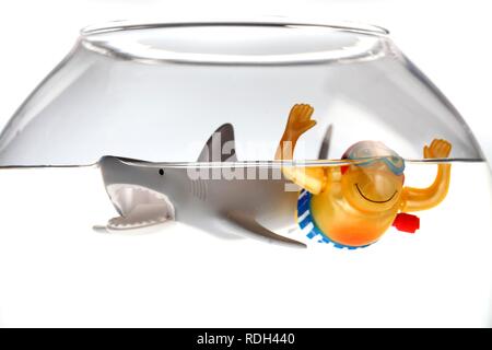 Wind-up toy figure of a boy swimming with a shark in a fish bowl, illustration Stock Photo