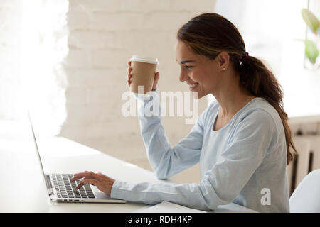 Smiling happy woman using laptop and drinking coffee Stock Photo