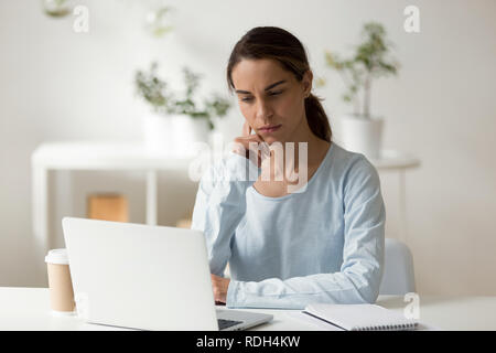 Serious female student using laptop, working on difficult projec Stock Photo