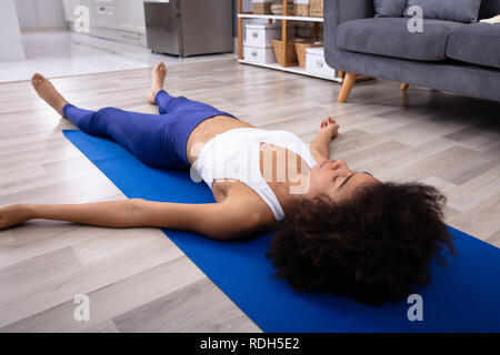Athletic Young Woman Lying On Blue Yoga Mat Over The Hardwood Floor Stock Photo