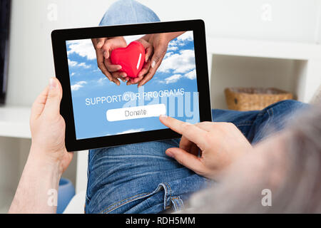 Close-up Of A Man's Hand Using Digital Tablet For Donation Stock Photo