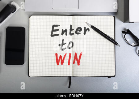 High Angle View Of Enter To Win Text Written On Notebook Over Desk Stock Photo