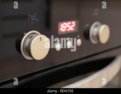 closeup of control dials and buttons of modern kitchen oven. selective focus on closest knob with blurred digital display Stock Photo