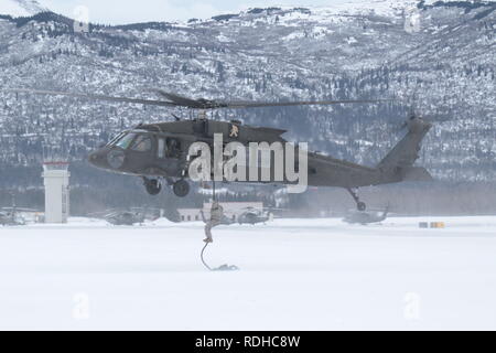 Soldiers from 1st Stryker Brigade Combat Team, U.S. Army Alaska, train USARAK and 4th Infantry Brigade Combat Team (Airborne) Soldiers on the Army Fast Rope Insertion/Extraction System at Bryant Army Airfield on Joint Base Elmendorf-Richardson Jan. 16, 2019. USARAK Soldiers conducted three FRIES descents from a UH60 Blackhawk helicopter in sub-freezing temperatures. Stock Photo