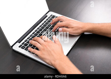 A man is working by using a laptop computer on vintage wooden table. Hands typing on a keyboard. Top view, business office workplace Stock Photo