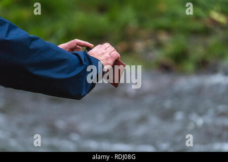 Old man hands holding a phone. Senior man with smart phone taking pictures outdoors Stock Photo