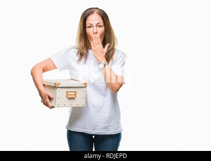 Middle age hispanic woman moving holding packing box over isolated background cover mouth with hand shocked with shame for mistake, expression of fear Stock Photo